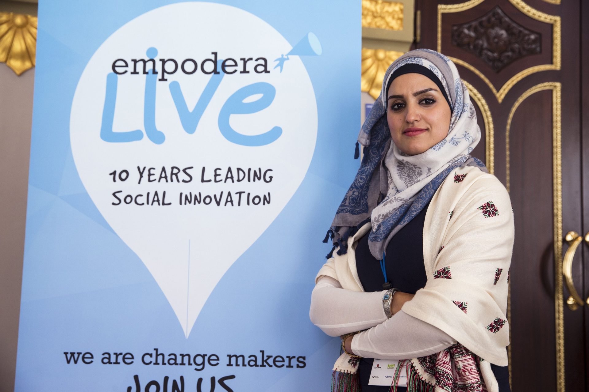 MENA Alliances Group founder Abeer Abu Ghaith, Palestine's first high-tech entrepreneur, next to the symposium poster ""Empower Live""    held in Malaga, 2016. Businesswomen in the Middle East are stuck between glass walls and ceilings.