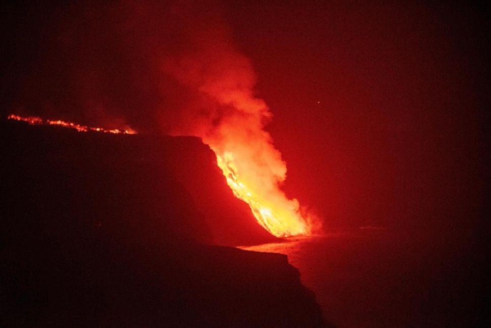 La colada de lava que emerge de la erupción volcánica de La Palma ha llegado esta noche al mar en una zona de acantilados en la costa de Tazacorte. EFE/Miguel Calero
