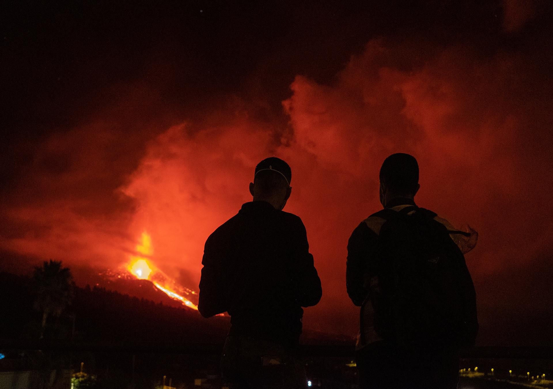 Dos jóvenes observan esta madrugada la erupción del volcán de La Palma desde la localidad de Tajuya, en el municipio de El Paso. EFE/Carlos de Saá