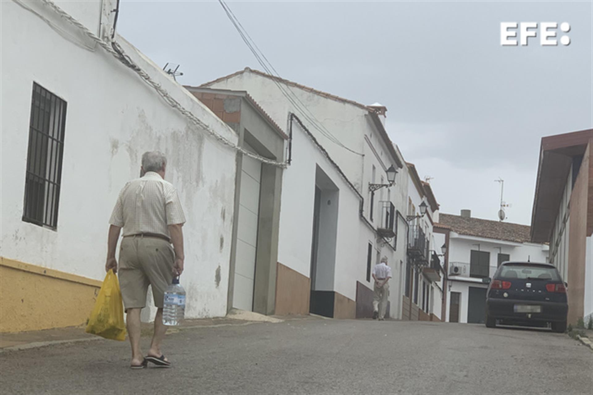 Un vecino de Cumbres Mayores (Huelva) transporta una botella de agua para consumir en su casa, en un municipio en el que las restricciones en el consumo de agua potable por el bajo nivel de sus acuíferos, hace que sus casi 1.800 vecinos no cuenten con agua corriente este fin de semana 22 horas seguidas. EFE/Fermín Cabanillas