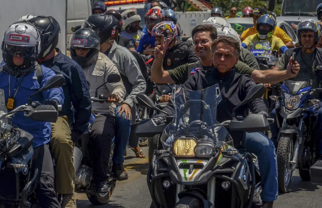 El presidente de Brasil, Jair Bolsonaro (d), conduce una motocicleta durante en un acto de campaña para las elecciones el próximo domingo, en la ciudad de Juazeiro, en el estado de Bahia (Brasil). EFE/Felipe Iruatã
