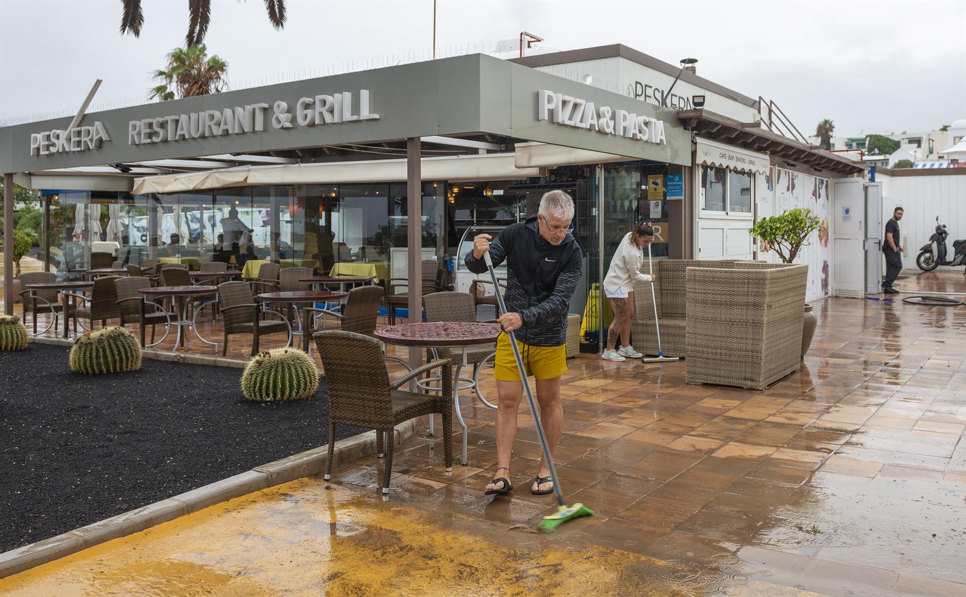 La tormenta tropical Hermine ha dejado lluvias moderadas en la isla de Lanzarote. En la imagen, empleados de un restaurante de Costa Teguise barren el agua que se acumula junto a su negocio. EFE/Adriel Perdomo