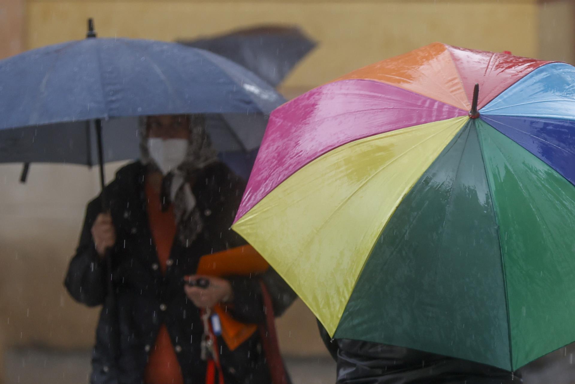 Unas personas se protegen de la lluvia con paraguas. EFE/ Kai Forsterling/Archivo