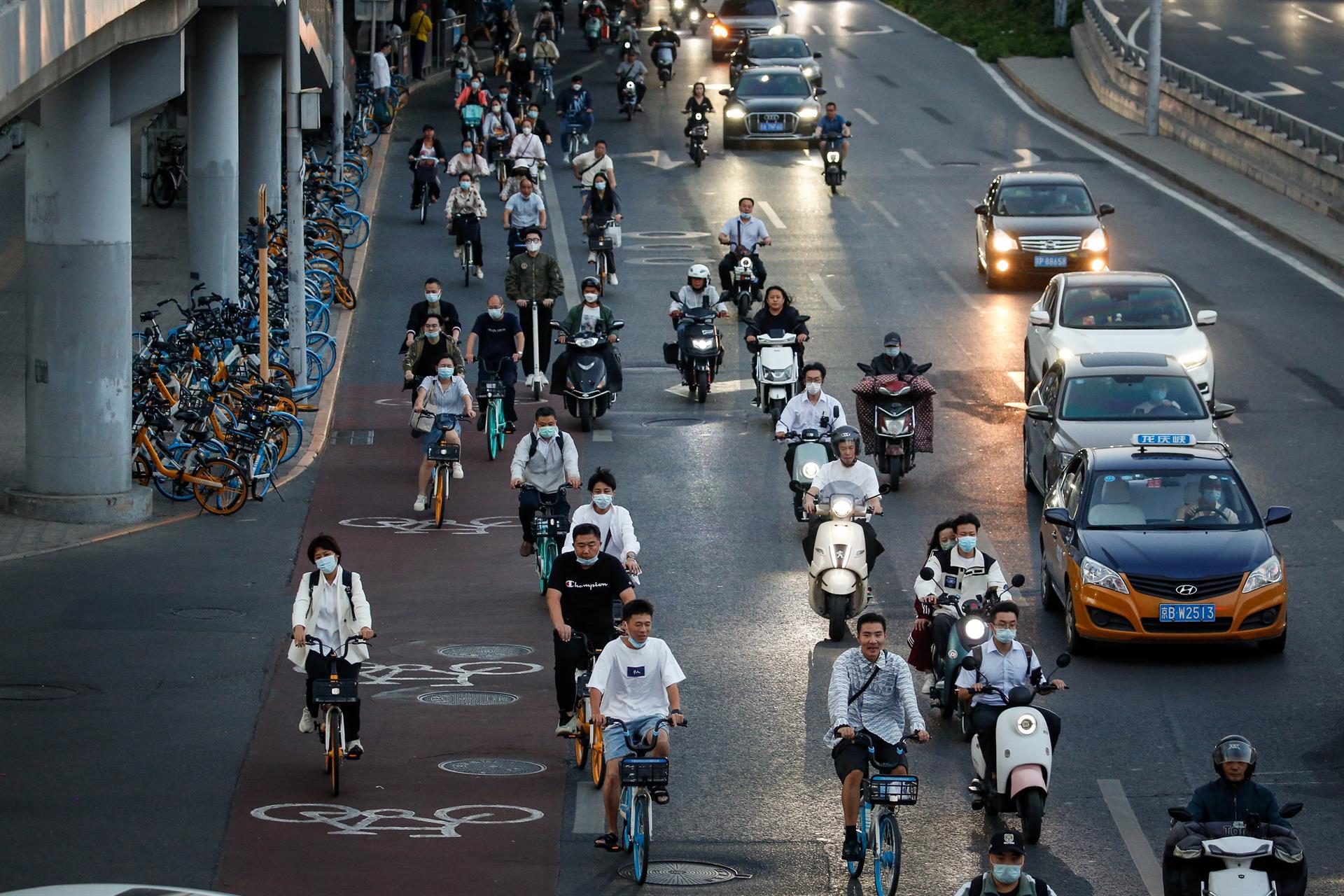 Personas circulan en bicicleta junto al tráfico en el distrito central de negocios de Pekín este 21 de septiembre. EFE/EPA/MARK R. CRISTINO