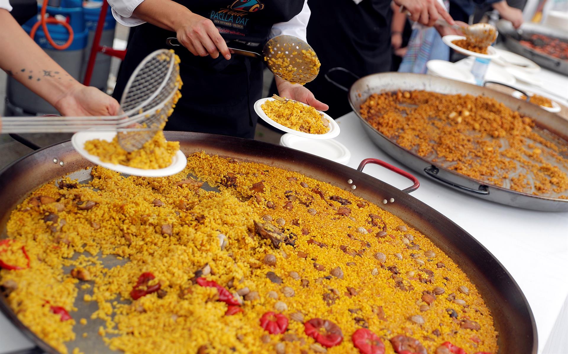 Varias personas reparten paella en la plaza del Ayuntamiento de València , en el Día Internacional de este plato (World Paella Day). EFE/Kai Försterling/Archivo