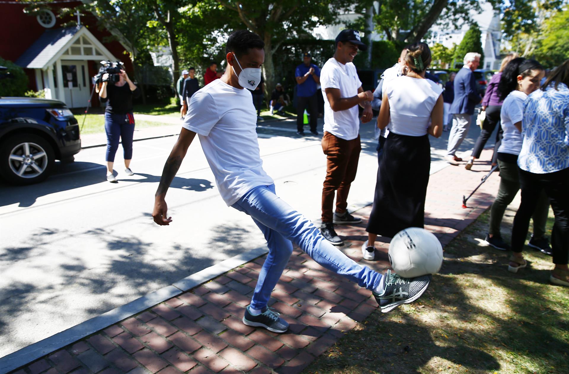 A migrant who is part of a group of nearly 50 migrants from Venezuela who were flown to the island of Martha's Vineyard off Cape Cod, Massachusetts on 14 September plays with a soccer ball at the parish house at St. Andrew's Episcopal Church in Edgartown, Massachusetts, USA, 15 September 2022. EPA-EFE/CJ GUNTHER
