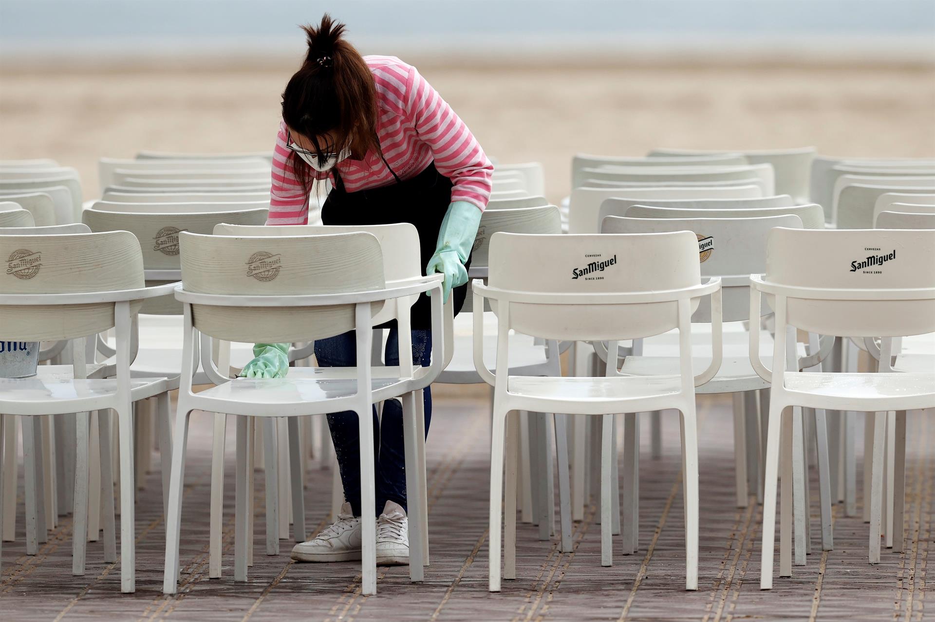 Una empleada limpia las sillas de un restaurante del paseo marítimo de València. EFE/Kai Försterling