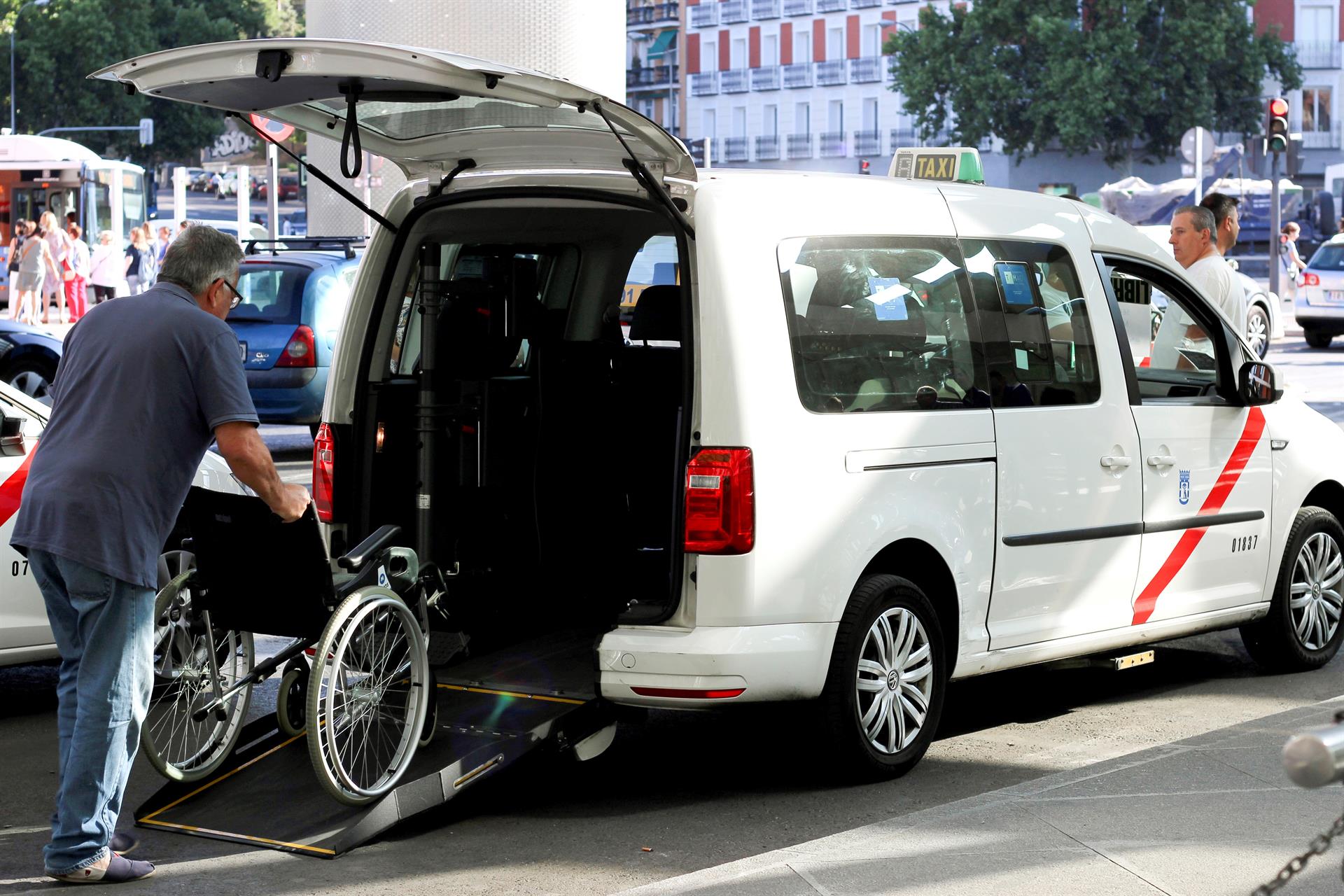 Un taxista, en servicios mínimos atiende a una a familia con un niño con movilidad reducida. EFE/Eduardo Oyana/Archivo