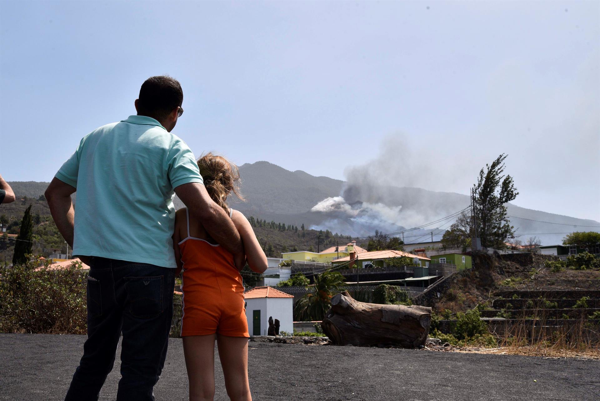 Varias personas observan el volcán de Cumbre Vieja que este sábado continúa su actividad, registrando una intensa emisión de gases a través de un amplio campo de fumarolas. La colada de material magmático que emergió ayer de los dos nuevos centros emisores de lava que se abrieron a unos 600 metros del cono principal del volcán de Cumbre Vieja, en La Palma, ha tomado hoy contacto con la primera de las coladas que formó esta erupción volcánica. EFE/MIGUEL CALERO