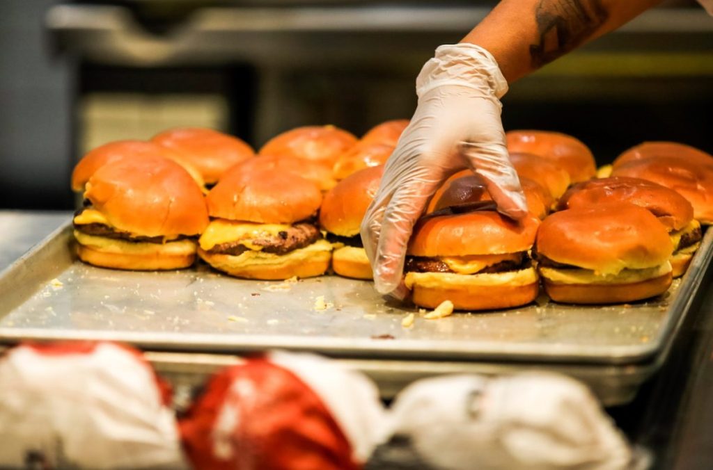 Una persona prepara hamburguesas en un puesto de comida rápida.