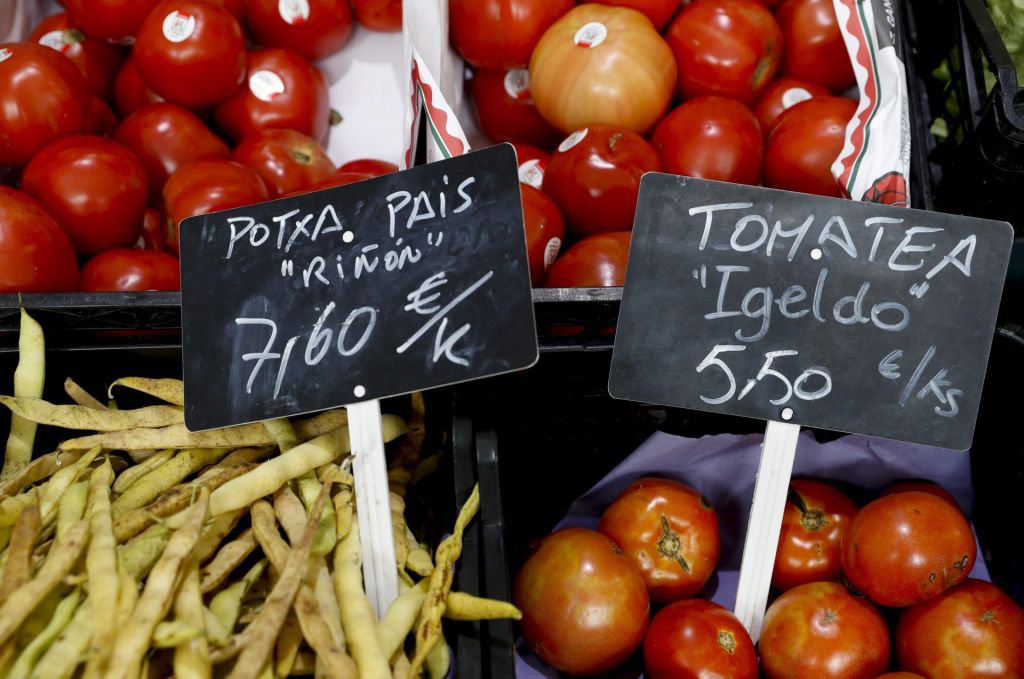 Un puesto de tomates con los precios en un mercado