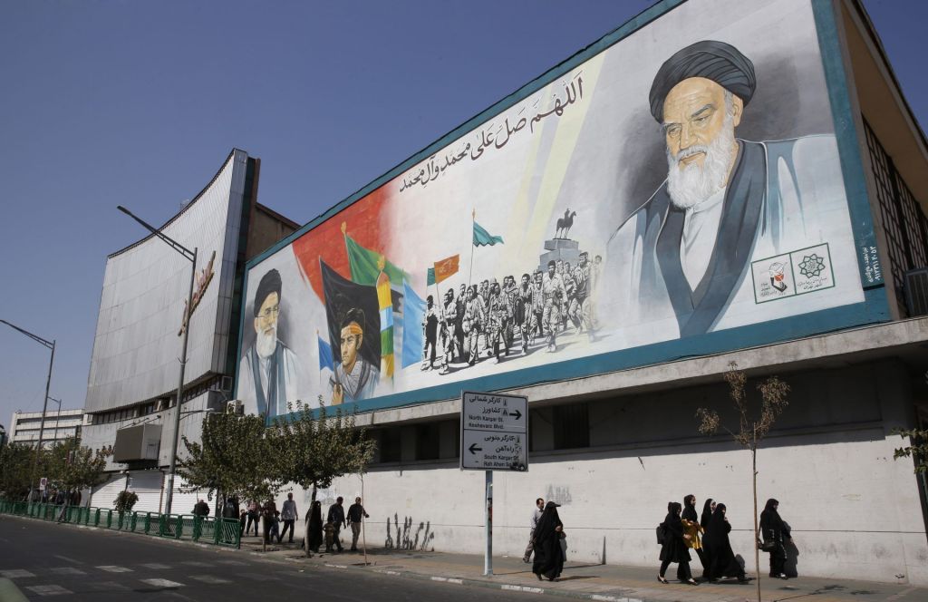 Ciudadanos iraníes se dirigen a la oración del viernes en Teherán bajo un muural con las imágenes del ayatolá Jomeini (d) y el líder supremo iraní, Alí Jamenei. Irán vive una oleada de protestas.