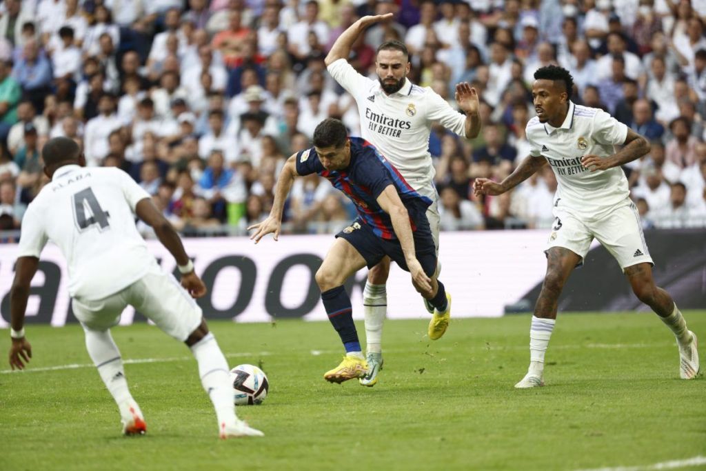 El delantero del FC Barcelona Robert Lewandowski lucha por el balón con varios jugadores del Real Madrid.