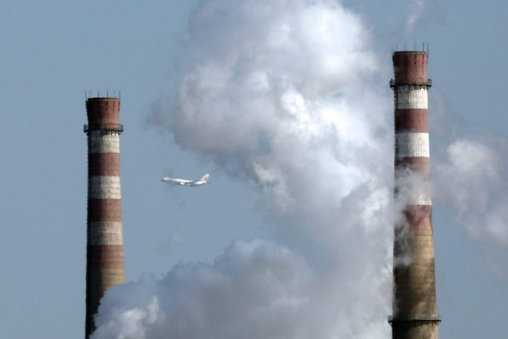 Un avión vuela entre dos torres de refrigeración y una columna de humo en Pekín (China), en una imagen de archivo.