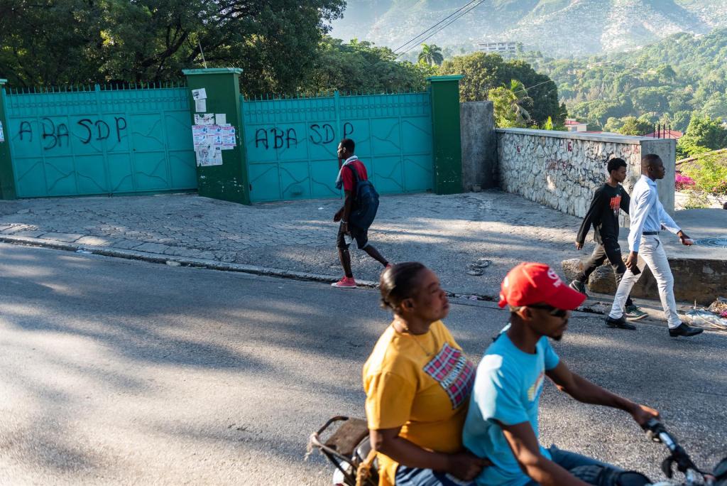 Personas caminan frente a una de las escuelas cerradas hoy, en Puerto Príncipe (Haití). EFE/Johnson Sabin
