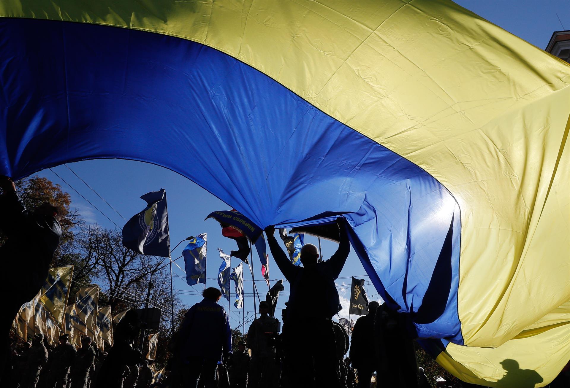 Fotografía de archivo de un grupo de personas ondeando una bandera nacional ucraniana gigante en el centro de Kiev. EFE/EPA/SERGEY DOLZHENKO