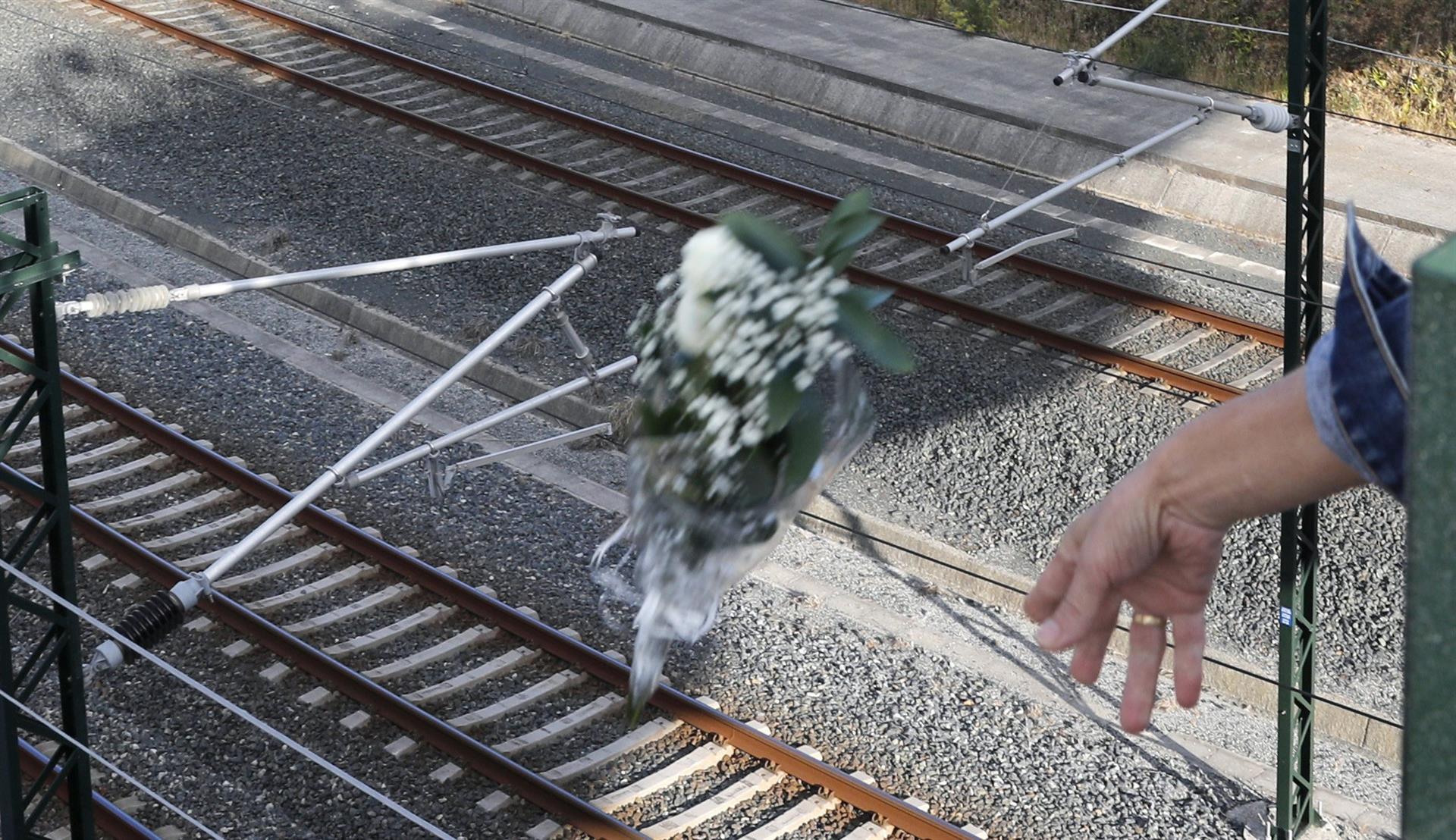 Imagen de archivo de una persona arrojando flores en la curva de Angrois donde hace nueve años murieron ochenta personas y casi centenar y medio resultaron heridas en el accidente del Alvia que descarriló en Santiago. EFE/Lavandeira jr