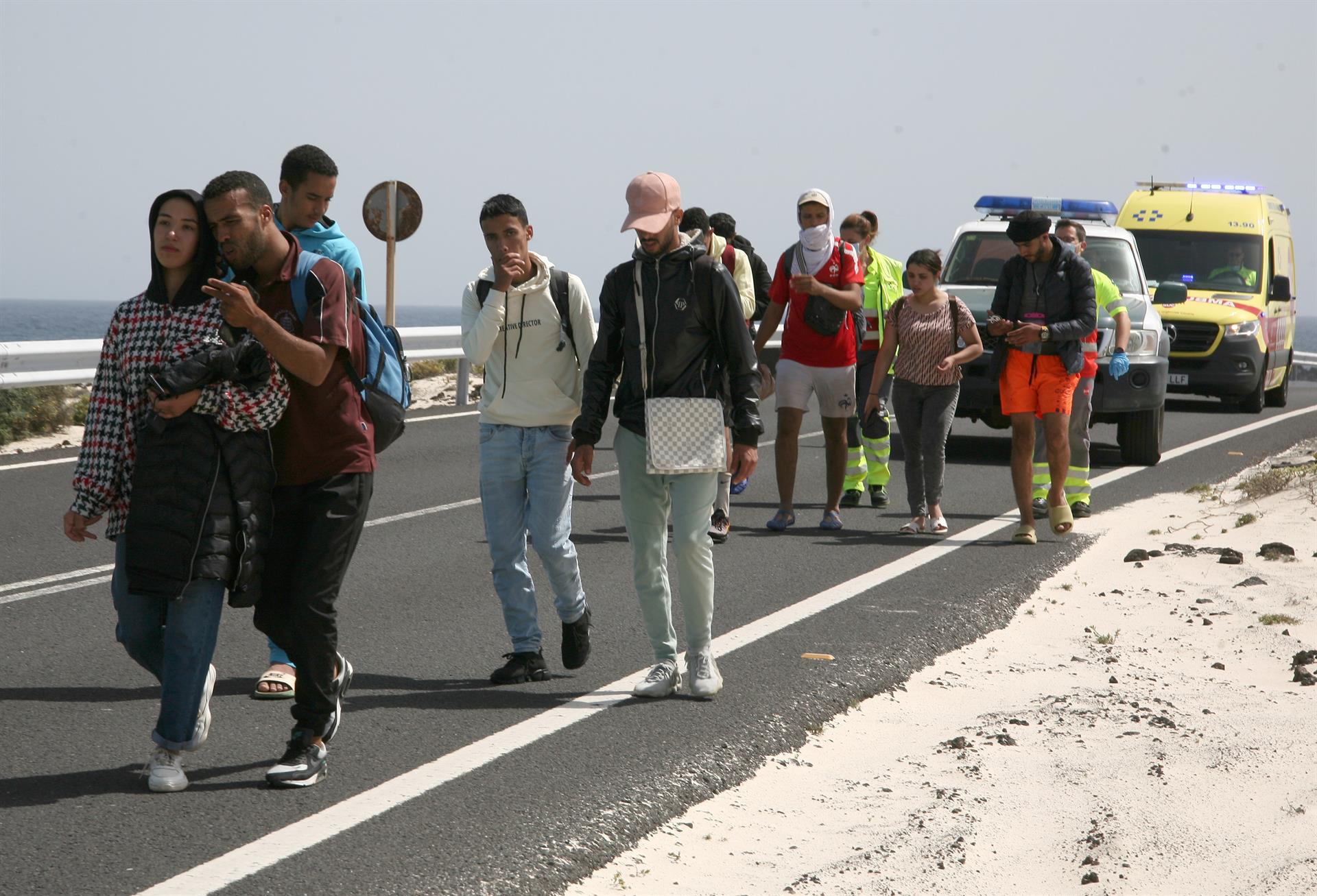 La Guardia Civil y un equipo de emergencias acompaña a varios de los ocupantes de la neumática por la carreta que conduce a la playa de Caletón Blanco, en el municipio de Haría, donde desembarcaron. EFE/Adriel Perdomo