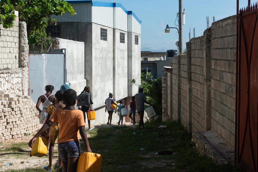 Menores de edad buscan hoy agua para llevar a sus hogares mientras las escuelas permanecen cerradas, en Puerto Príncipe (Haití). EFE/Johnson Sabin