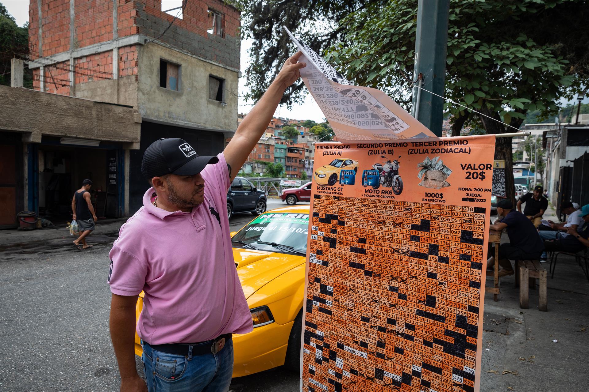 Luis Sánchez muestra el pendón con los premios e información de una rifa, el 30 septiembre de 2022, en Caracas (Venezuela). EFE/Rayner Peña R.