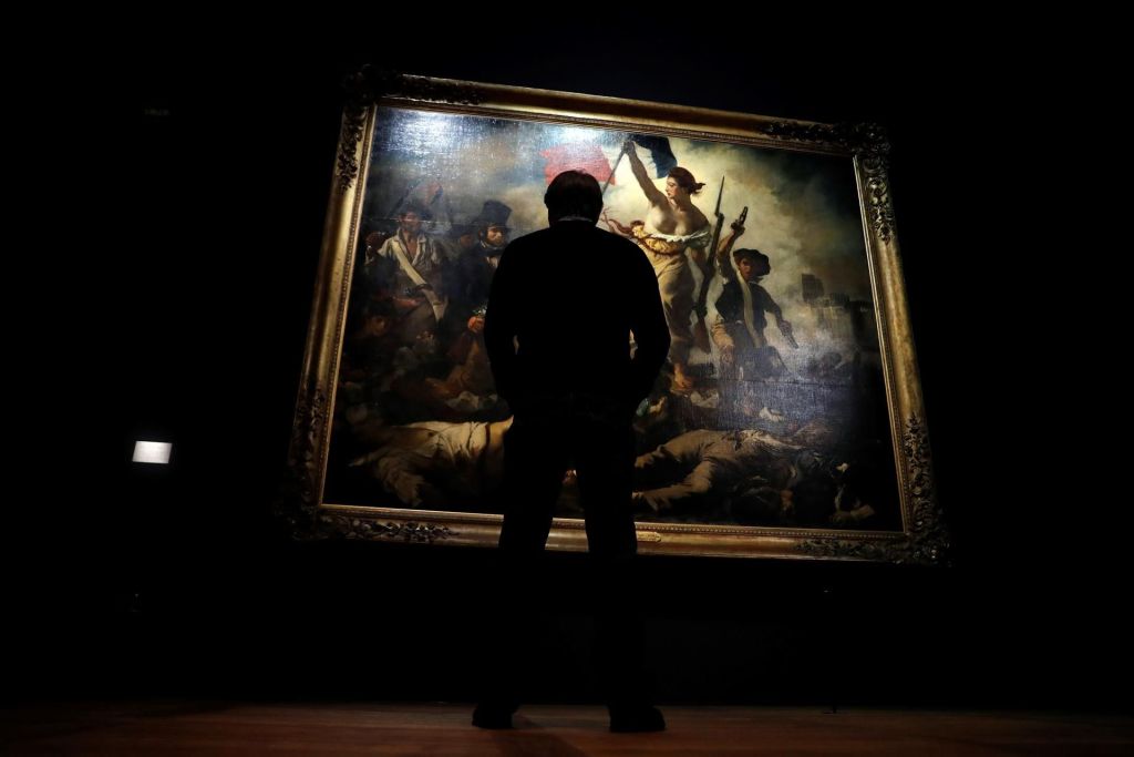 Un visitante observa la obra del pintor galo Eugene Delacroix "La libertad guiando al pueblo", en el que en 2003 una joven realizó una inscripción con rotulador.