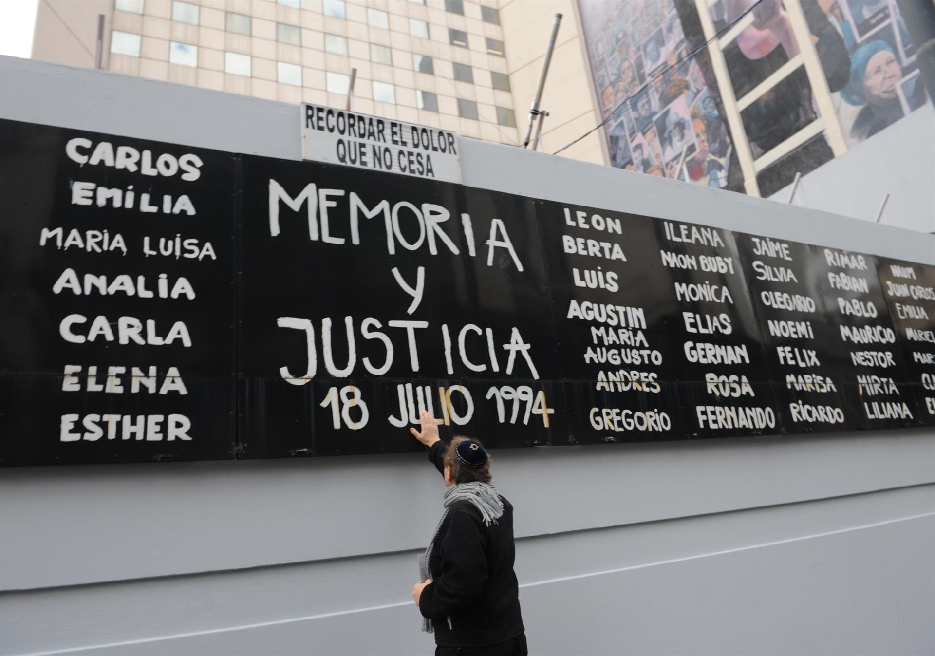 Un hombre toca un cartel con nombres de víctimas durante un acto conmemorativo del atentado contra la mutua judía AMIA, en una fotografía de archivo. EFE/ Enrique G. Medina