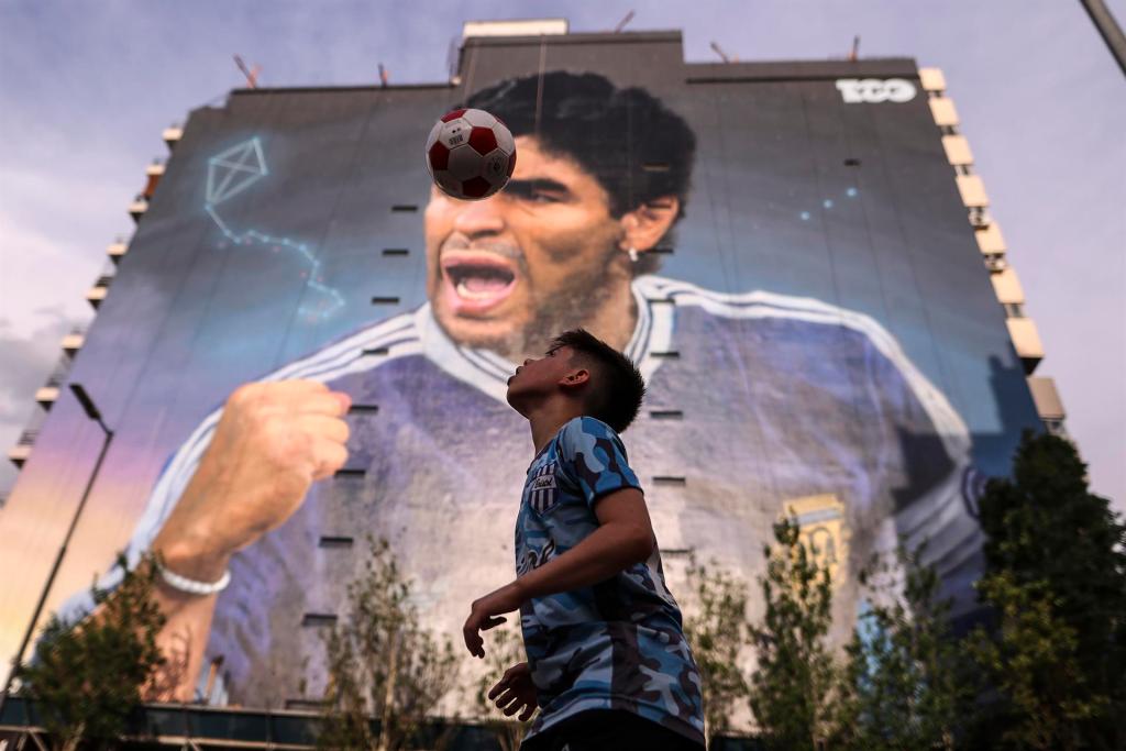 Niños juegan fútbol cerca al mural en honor a Diego Armando Maradona realizado por Martín Ron, el 28 de octubre de 2022 en Buenos Aires (Argentina). EFE/Juan Ignacio Roncoroni
