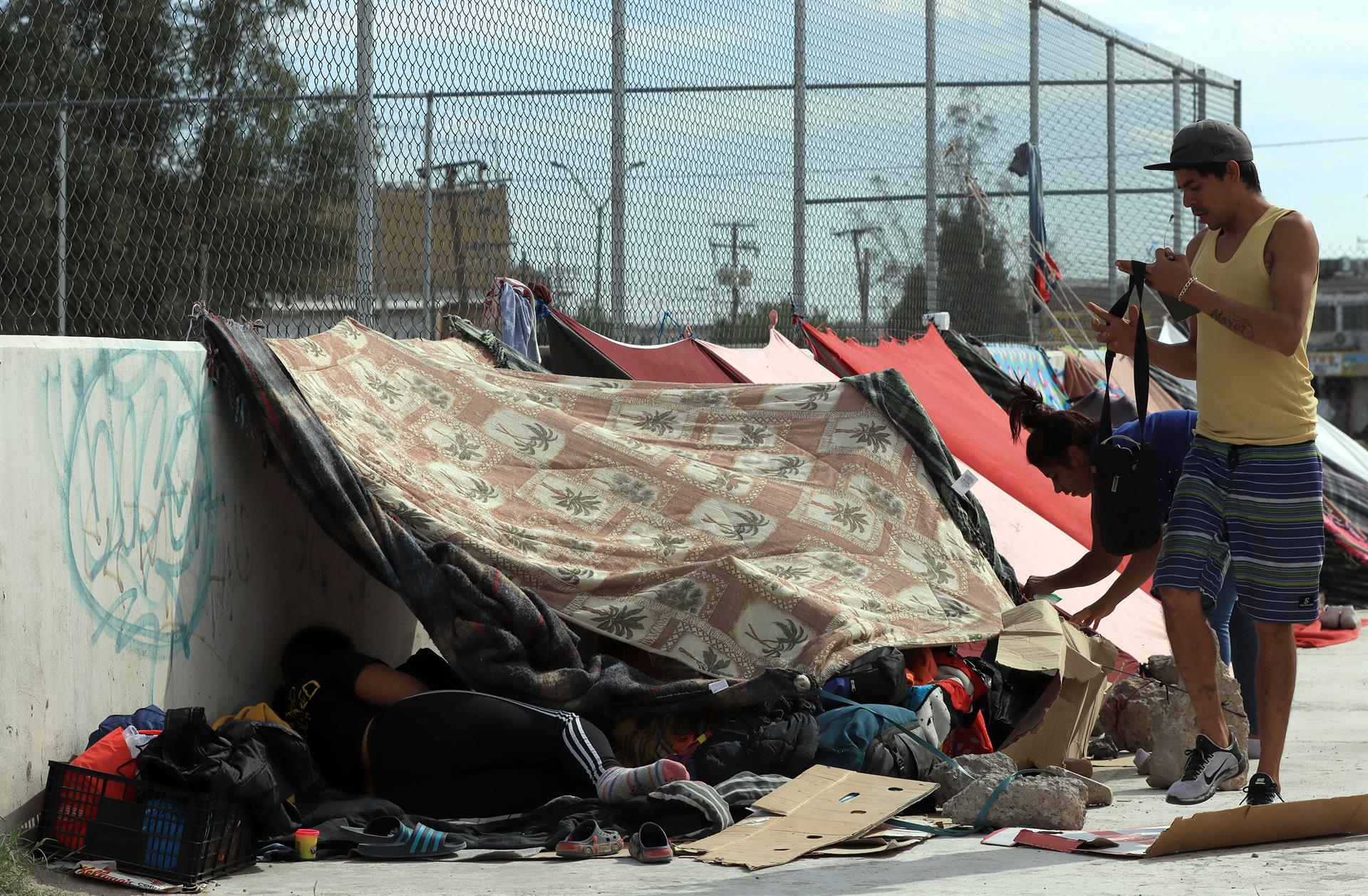 Personas migrantes de origen venezolano descansan en la calle cerca de la barda fronteriza entre México y Estados Unidos, el 23 de octubre de 2022, en Ciudad Juárez, Chihuahua (México). EFE/ Luis Torres