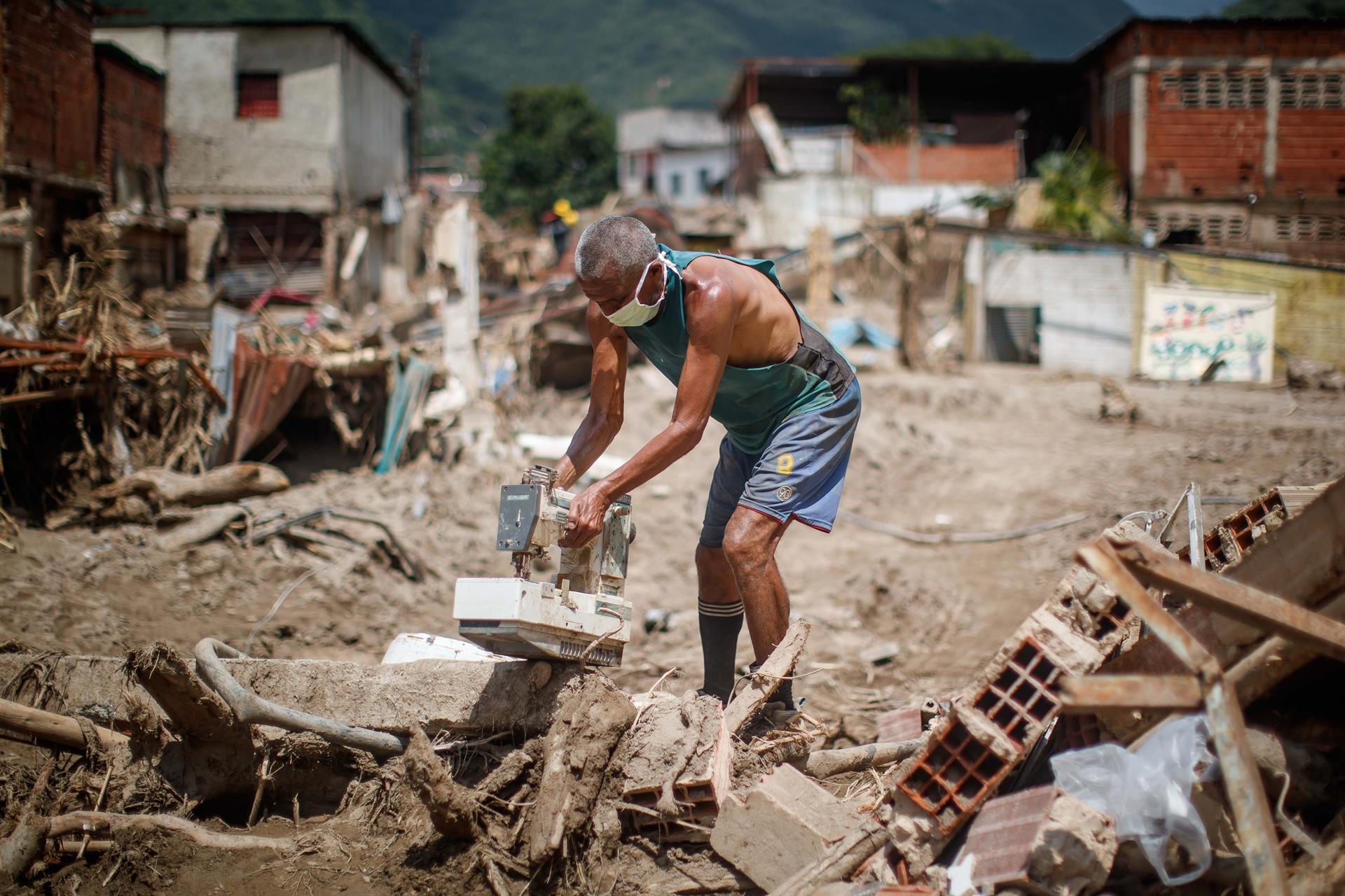 Personas buscan objetos para rescatar entre los escombros tras derrumbes provocados por las fuertes lluvias, hoy, en Las Tejerías (Venezuela). EFE/ Miguel Gutiérrez