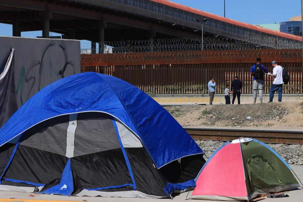 Personas migrantes de origen venezolano descansan en la calle cerca del muro fronterizo entre México y Estados Unidos, el 23 de octubre de 2022, en Ciudad Juárez, Chihuahua (México). EFE/ Luis Torres