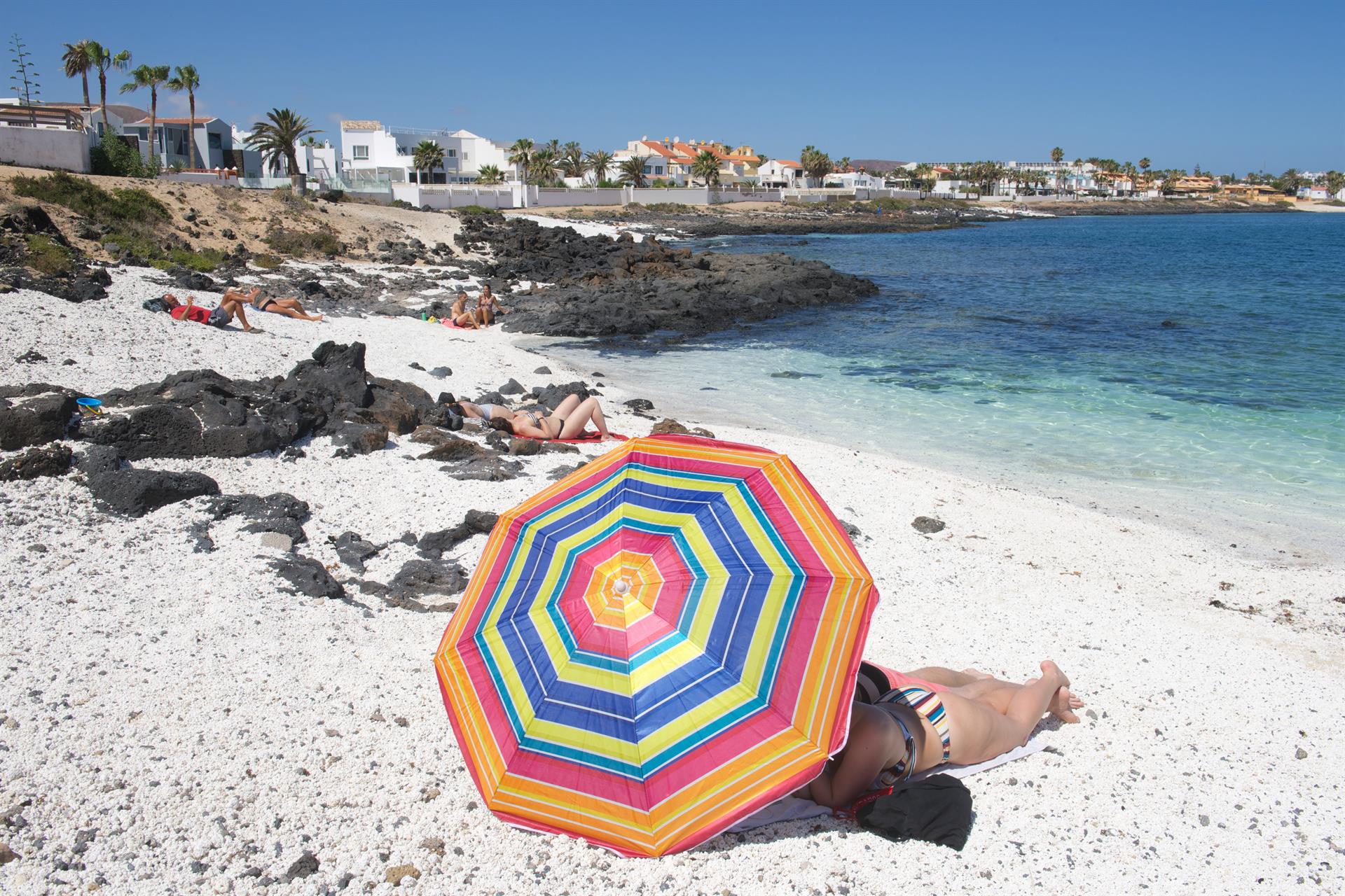 En la foto, turistas disfrutando de un día de playa en la localidad de Corralejo, en el norte de Fuerteventura. EFE/Carlos de Saá