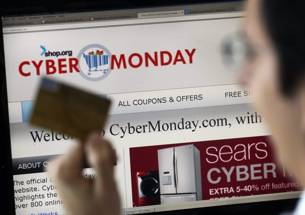 Un hombre sacas su tarjeta de crédito frente al ordenador para comprar en el 'cyber monday'
