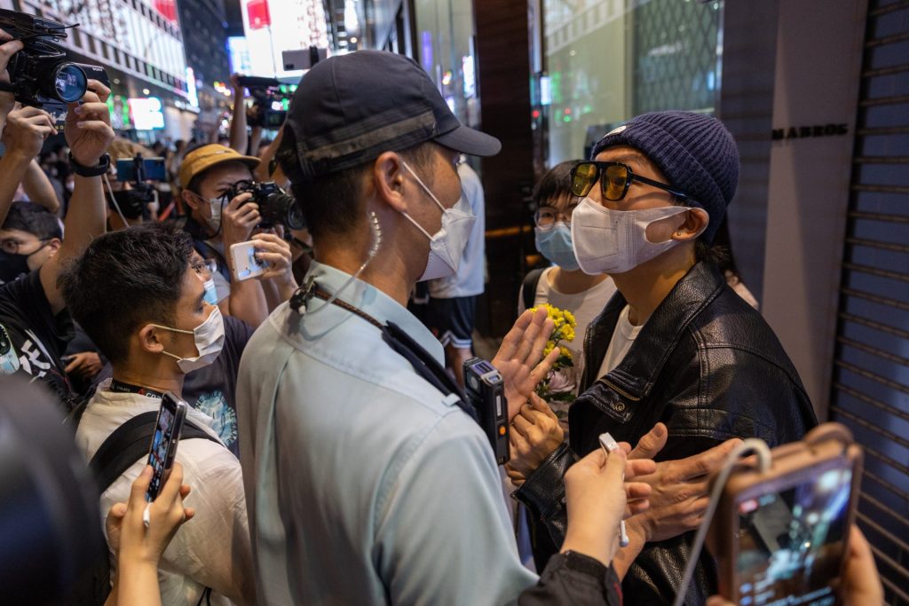 Un policía pide la documentación a un participante en una vigilia en Hong Kong por las víctimas del incendio de Urumqi, China. 