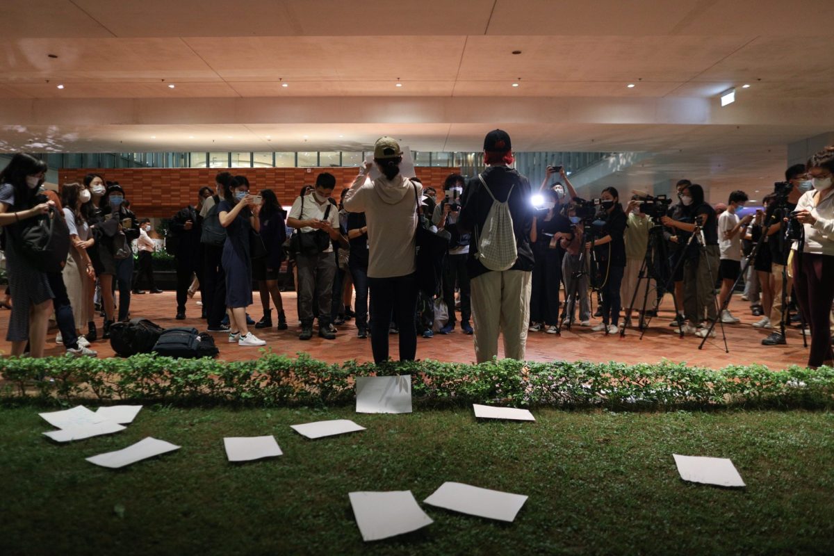 Estudiantes chinos sostienen hojas de papel en blanco durante una vigilia por las víctimas de la política de "covid cero" de las autoridades chinas, en la Universidad de Hong Kong.