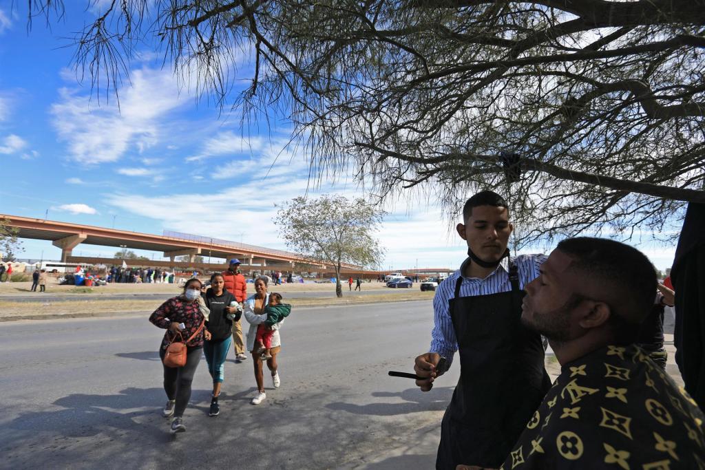 El migrante de origen venezolano, Adrián Cáceres, corta el cabello a una persona el 11 de noviembre de 2022 en Ciudad Juárez, Chihuahua (México). EFE/Luis Torres