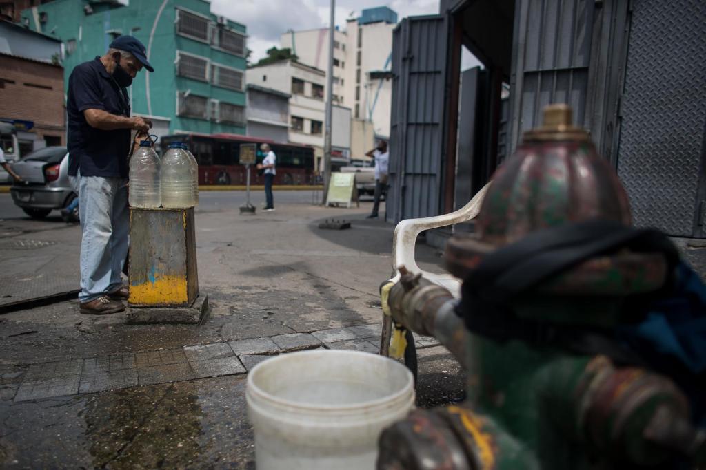 Un hombre recoge agua de una tubería callejera, el 26 de octubre de 2022, en Caracas (Venezuela). EFE/ Miguel Gutiérrez 
