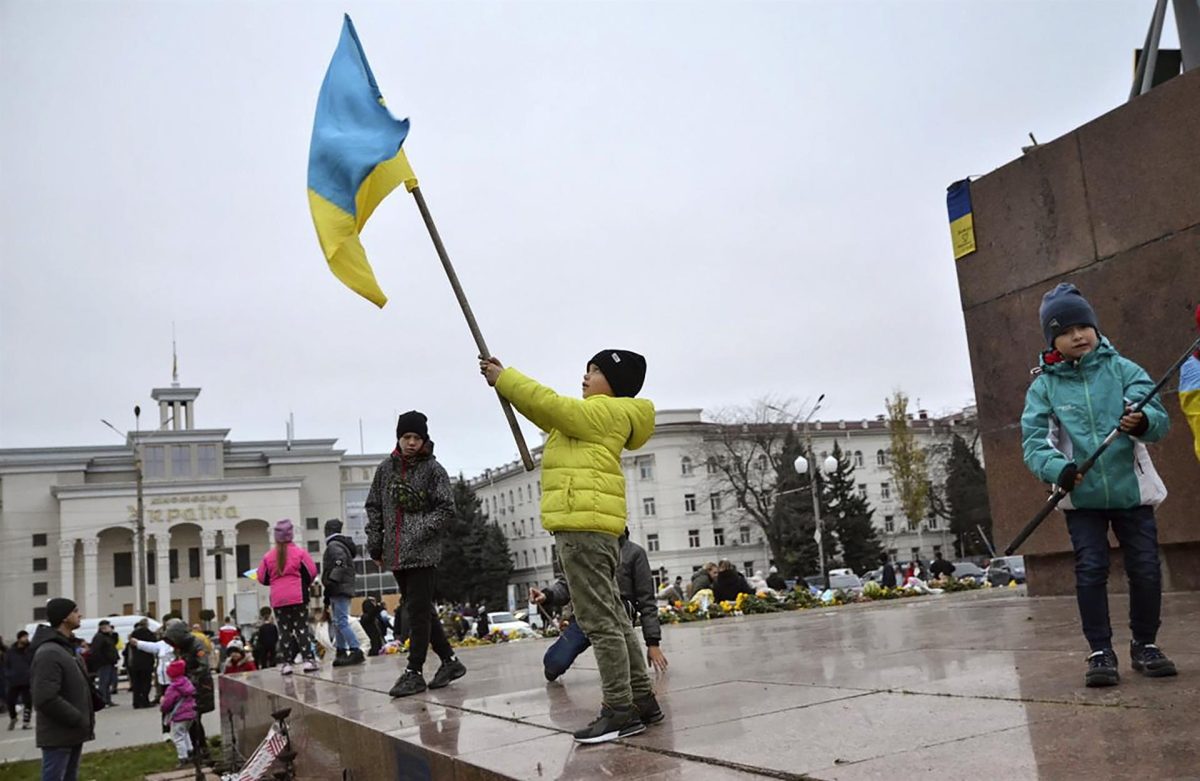 Niños ondean banderas ucranianas en la plaza principal de la ciudad de Jersón