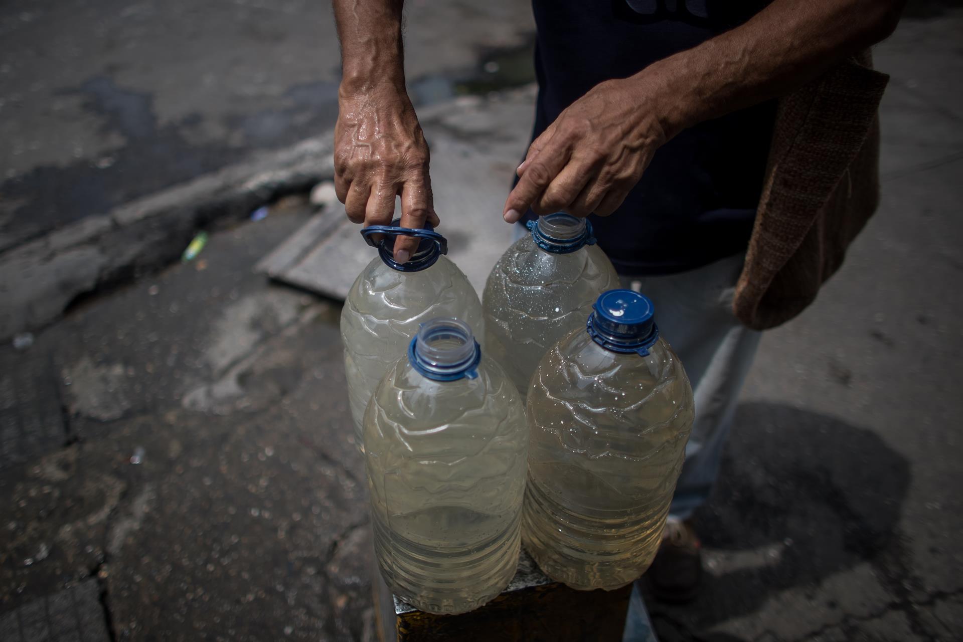 Un hombre recoge agua de una tubería callejera, el 26 de octubre de 2022, en Caracas (Venezuela). EFE/ Miguel Gutierrez