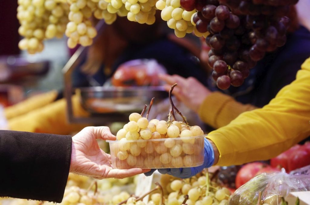 Un hombre compra unos racimos de uva en el Mercado Central en Valencia para celebrar la primera Nochevieja sin restricciones