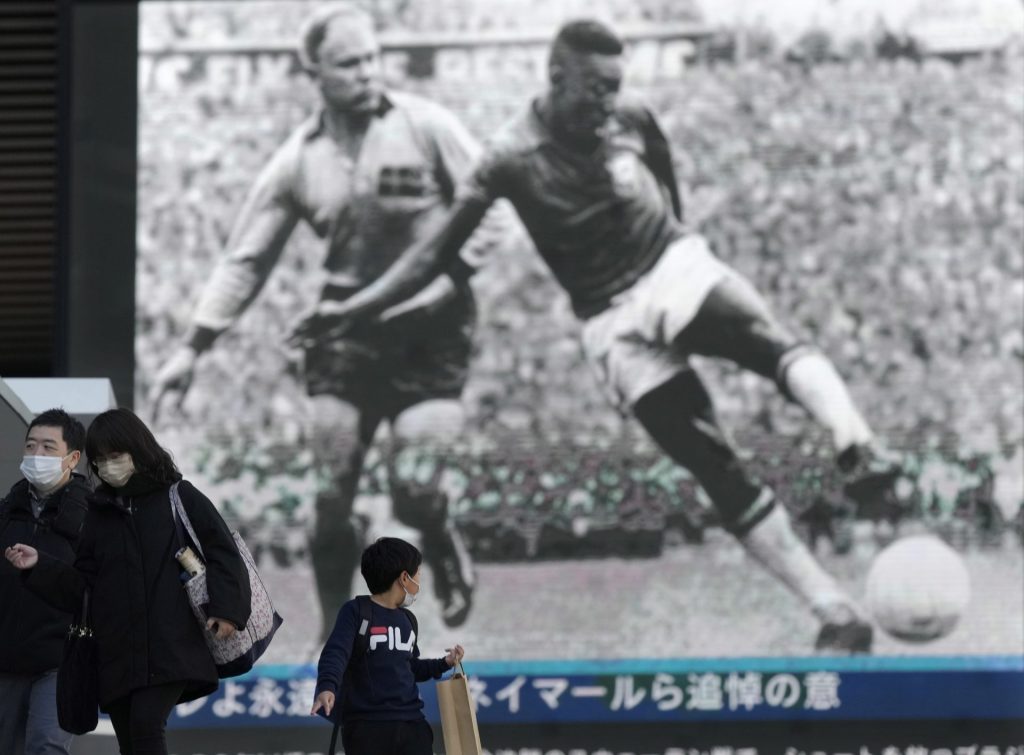 Un niño mira una gran pantalla que muestra la noticia de la muerte de Pelé en Tokio, Japón
