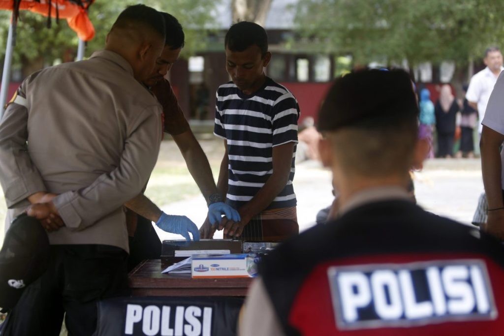 Agentes indonesios toman las huellas a un refugiado rohingya (C) en un proceso de identificación, en un refugio temporal proporcionado por el gobierno local de Aceh en Pidie, Aceh, Indonesia. 