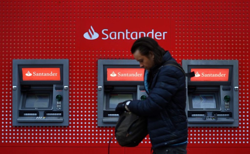 Un hombre pasa junto a unos cajeros del Banco Santander en Londres. 