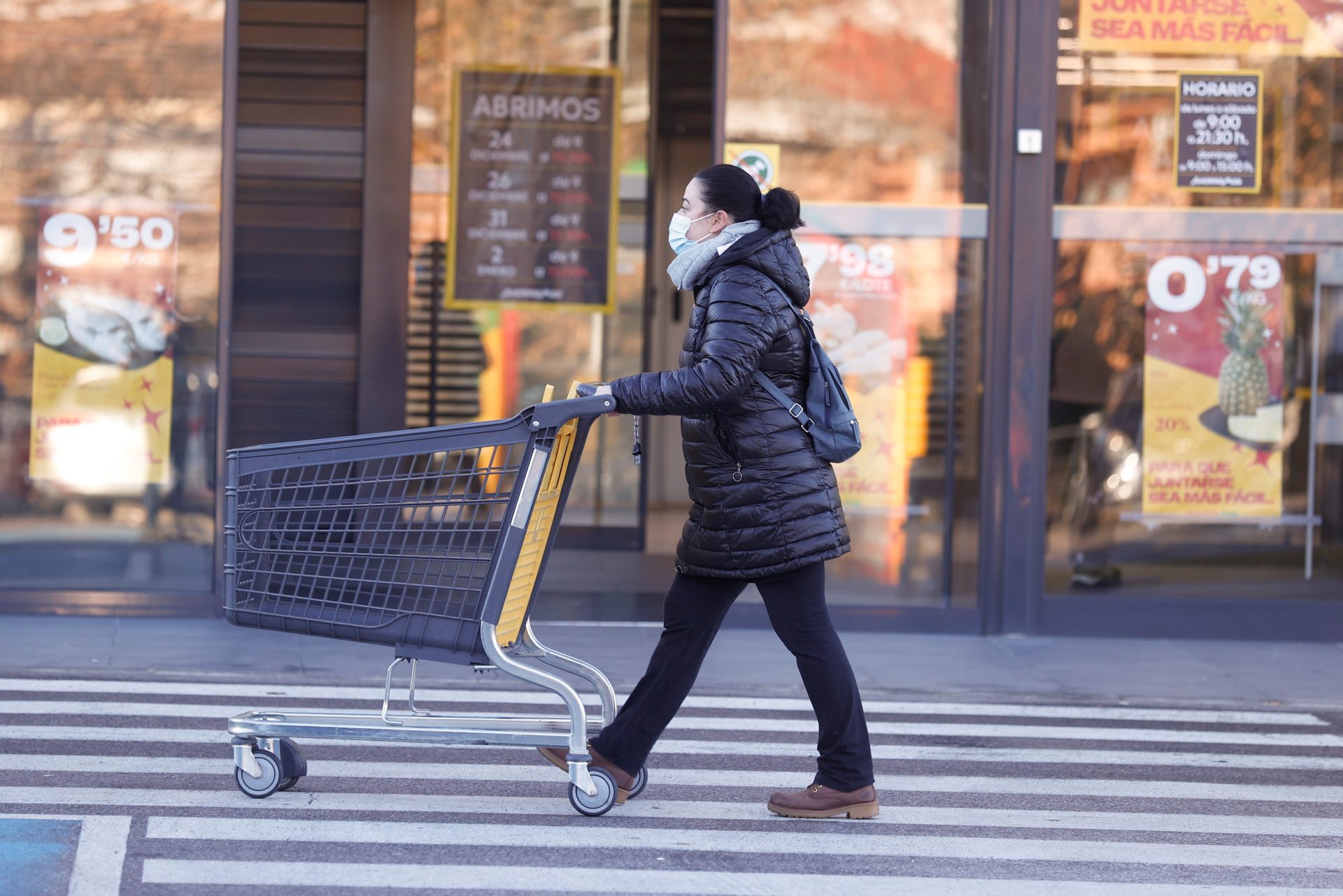 Una mujer camina con un carrito de un supermercado.