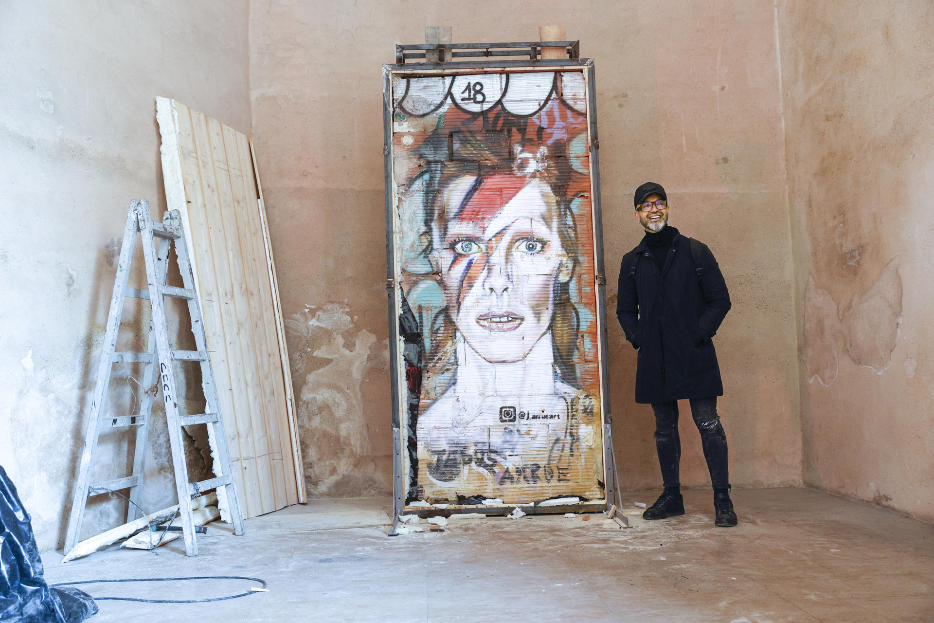 GRAFCVA245. VALENCIA, 12/12/2022.-El artista Jesus Arrúe posa con el el grafiti de David Bowie que dibujó en un muro de la ciudad de Valencia y que ha sido trasladado desde la ubicación callejera en el que fué creado, al museo del Carme, que va a contar desde ahora con esta obra de arte urbano. EFE/ Manuel Bruque