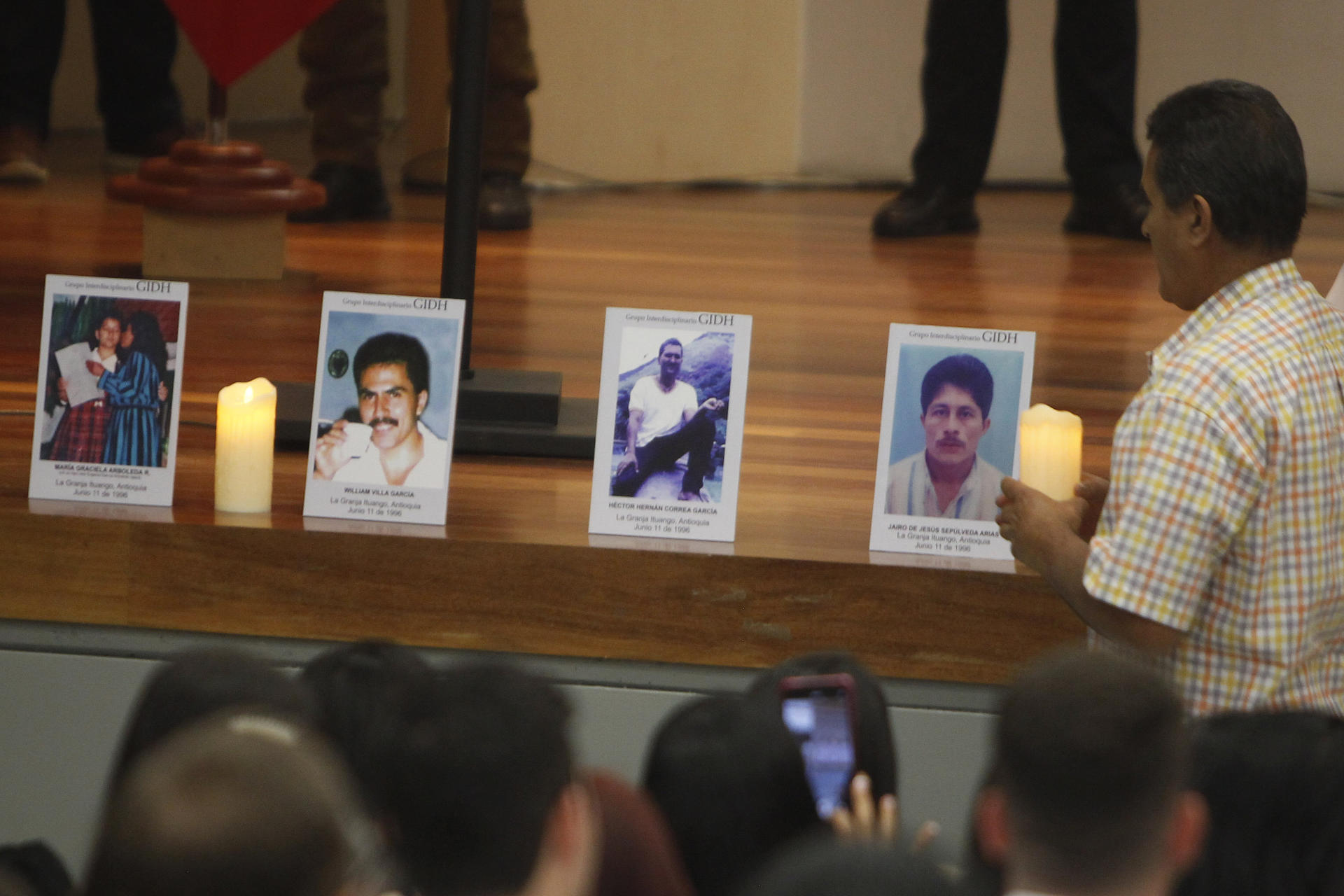 Un hombre pone una vela frente a una fotografía durante el Acto de reconocimiento de responsabilidad y pedido de perdón por las masacres de Ituango. EFE/Luis Eduardo Noriega A.