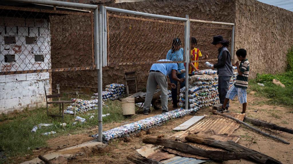 Miembros de la ONG "La Papelera Tiene Hambre" construyen un muro ecológico usando 'ecobloques' en la escuela Luz del Saber, el 7 de diciembre de 2022, en el barrio Ciudad Lossada, en Maracaibo (Venezuela). EFE/Henry Chirinos
