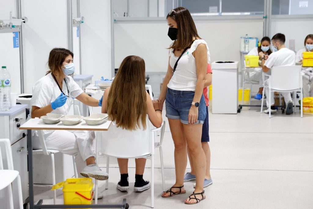 Una adolescente, acompañada de su madre, se vacuna contra la covid-19 en el hospital Enfermera Isabel Zendal de Madrid,
