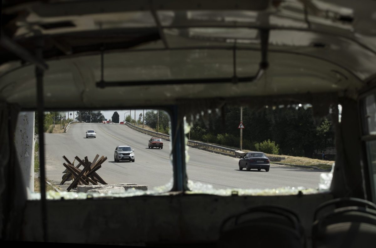 Automóviles pasan junto a un autobús destruido a un costado de la carretera que conduce a Dnipro (Ucrania).