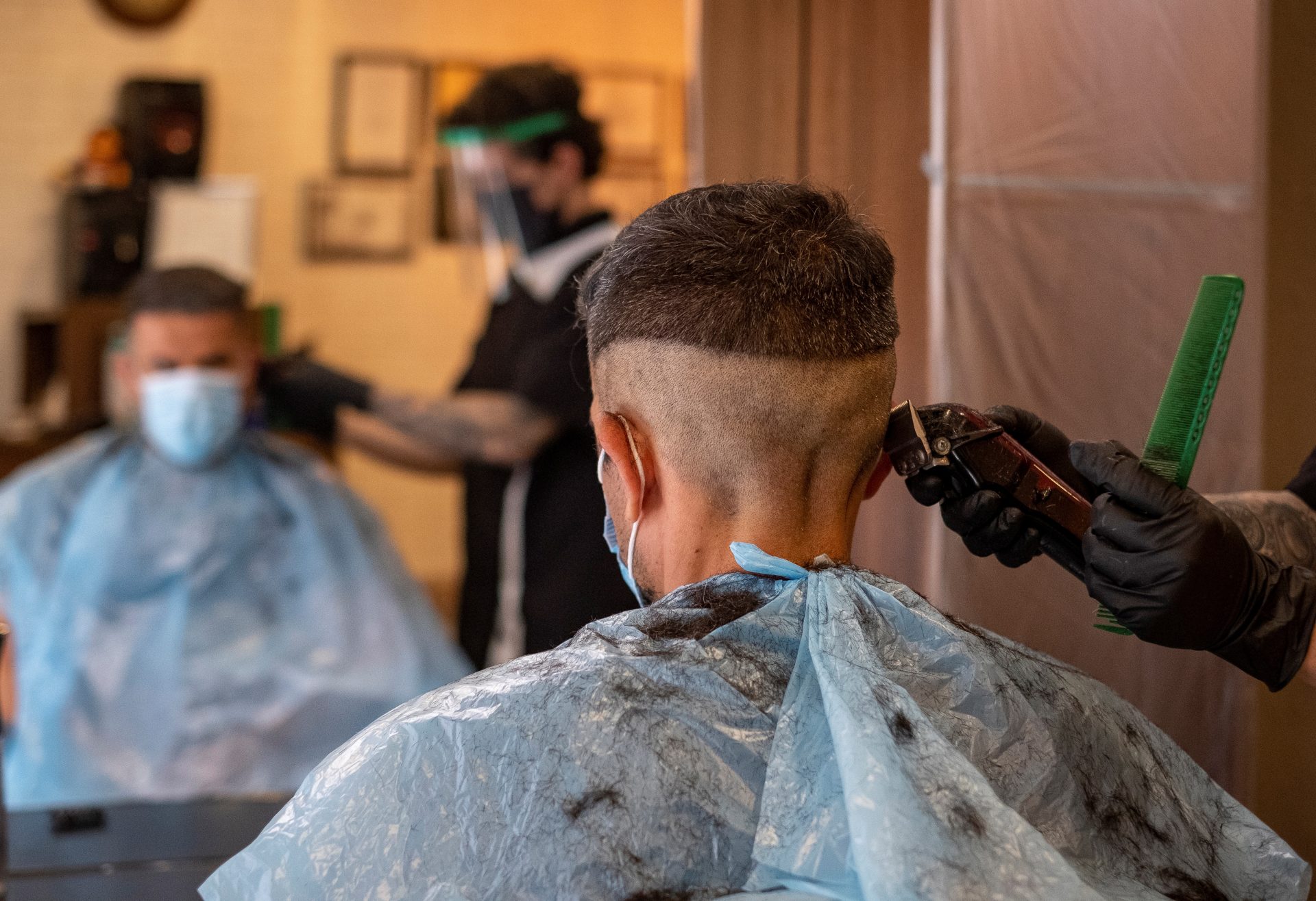 Un hombre atiende a un cliente en su peluquería.