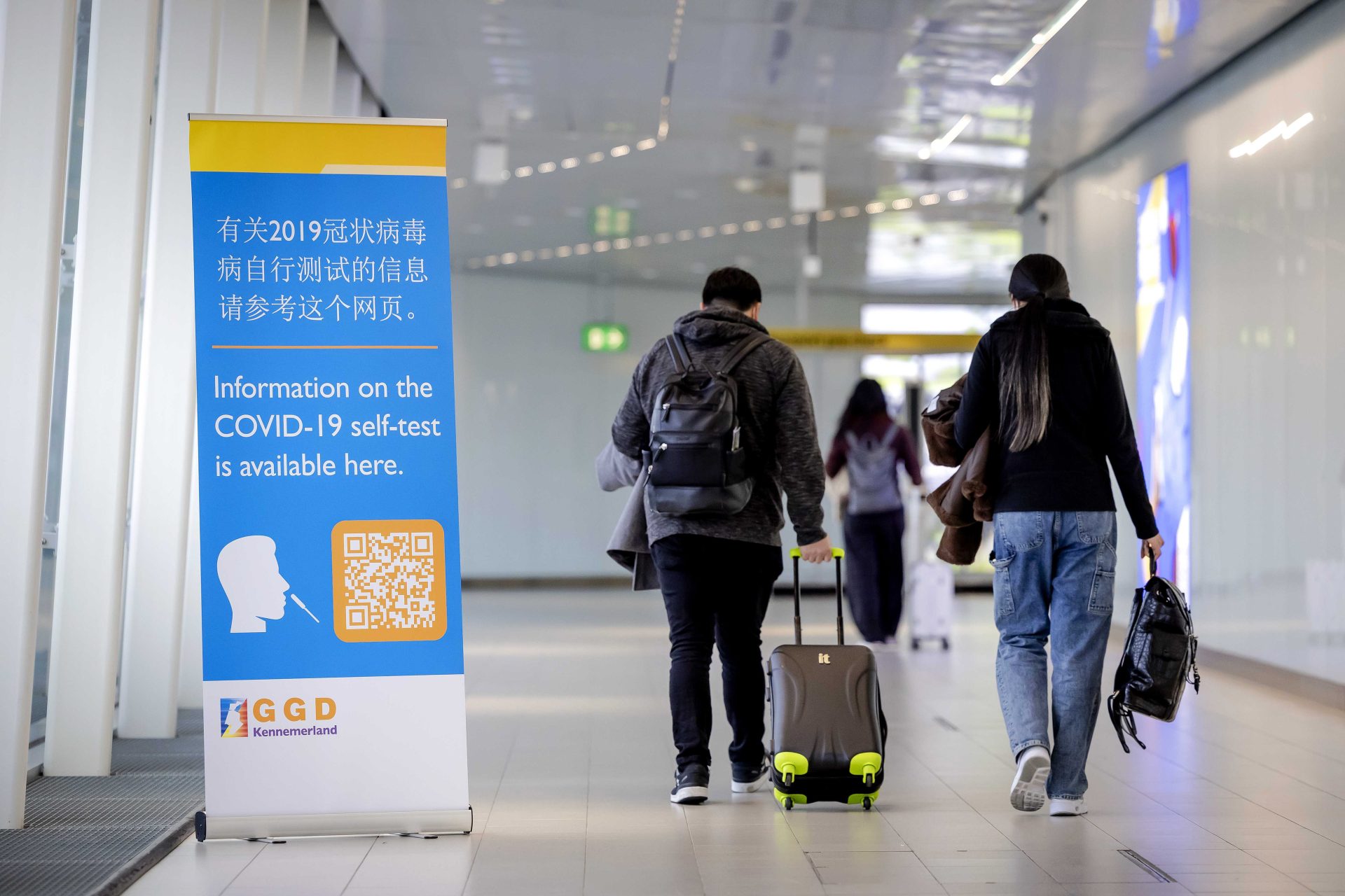 Los viajeros de China pasan frente a una pancarta con información y reciben una autotest gratuita de Covid-19 a su llegada a Schiphol, Países Bajos. La UE recomienda pedir pruebas de covid a los viajeros procedentes de China.